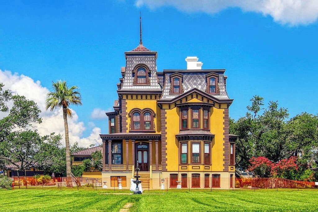 A large, yellow Victorian-style building with a prominent tower and multiple windows.