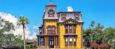 A large, yellow Victorian-style building with a prominent tower and multiple windows.