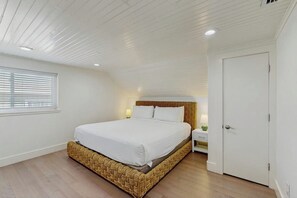 A bedroom with a single bed, a nightstand, a door, and a window with blinds. - El Cerrito Place - Unit B (Port Aransas)