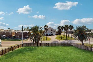 A residential area with a house, palm trees, and a fenced yard. - El Cerrito Place - Unit B (Port Aransas)