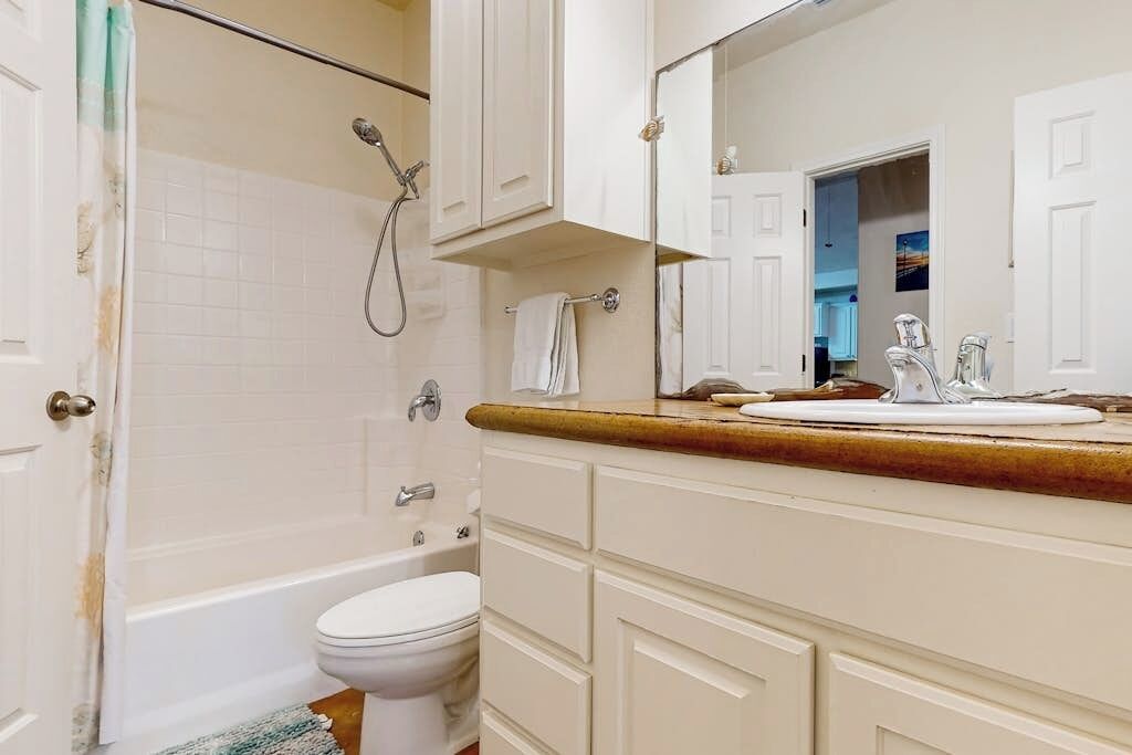 Un baño con bañera, inodoro y tocador con espejo.