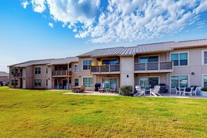 A multi-story residential building with balconies, outdoor seating, and a grassy lawn. - Beachaholic - Bay Views, Pool, Near the Beach (Rockport)