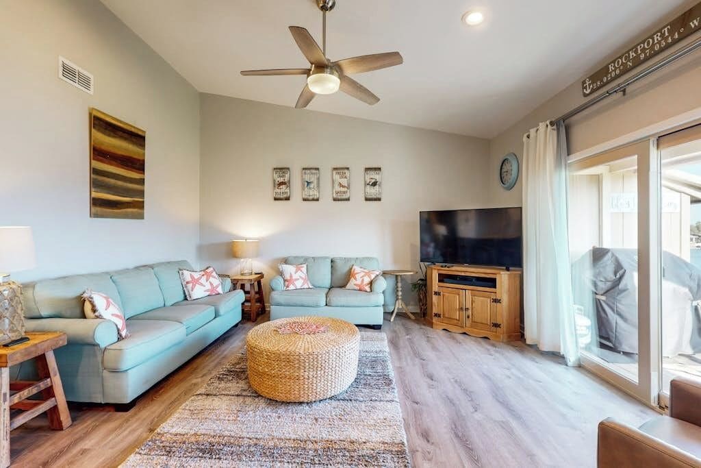 A living room with a sectional sofa, a television, and a ceiling fan.