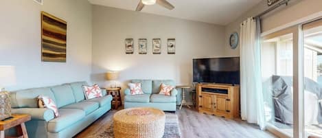 Una sala de estar con sofá seccional, televisor y ventilador de techo.