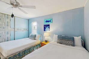 A room with two beds, a ceiling fan, a window, and wall art. - Beach Bum - Beach Gear, 2 Blocks to Shore (Port Aransas)