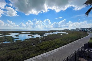 A coastal landscape with a paved walkway, grassy areas, and scattered water bodies. - Saltwater Serenity at the Reserve (Rockport)