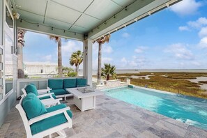 A covered outdoor area with a pool, seating, and a view of the beach. - Saltwater Serenity at the Reserve (Rockport)