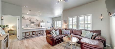 A spacious living room with a leather sofa, a coffee table, and a ceiling fan.