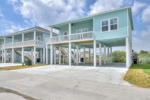 A two-story beachfront house with a covered patio and a staircase leading to the upper level. - Sea La Vie on Paradise (Rockport)