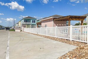 A residential street with houses, a white picket fence, and a clear sky. - Sea La Vie on Paradise (Rockport)