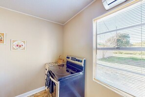 A compact kitchen with a stove, oven, and a window with blinds. - The Bay Breeze - Single-Level with Large Yard (Aransas Pass)
