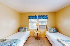 A room with two beds, a small round table, and a window with curtains. - The Bay Breeze - Single-Level with Large Yard (Aransas Pass)