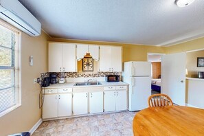 A compact kitchen with white cabinets, a microwave, a coffee maker, and a refrigerator. - The Bay Breeze - Single-Level with Large Yard (Aransas Pass)