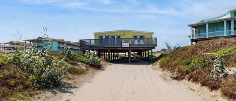 A beachfront property with a sandy path leading to a building marked '1908'.