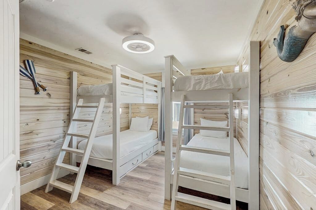 Dormitorio con literas, paredes de madera y una lámpara en el techo.