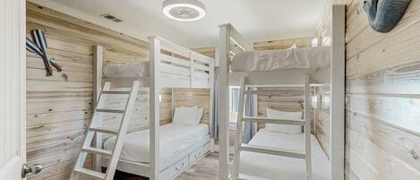 Een slaapkamer met een stapelbed, houten wanden en een plafondlamp.