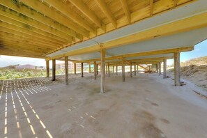 Ein Innenraum mit Holzbalkendecke und Säulen, einem Betonboden und Blick auf die umliegende Landschaft.
