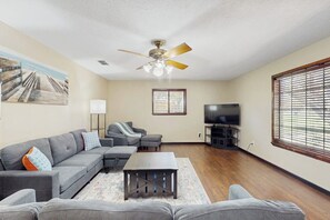 A living room with a sofa set, a coffee table, a television, and a ceiling fan. - Harris's Landing - House & Studio, Dog-Friendly (Rockport)