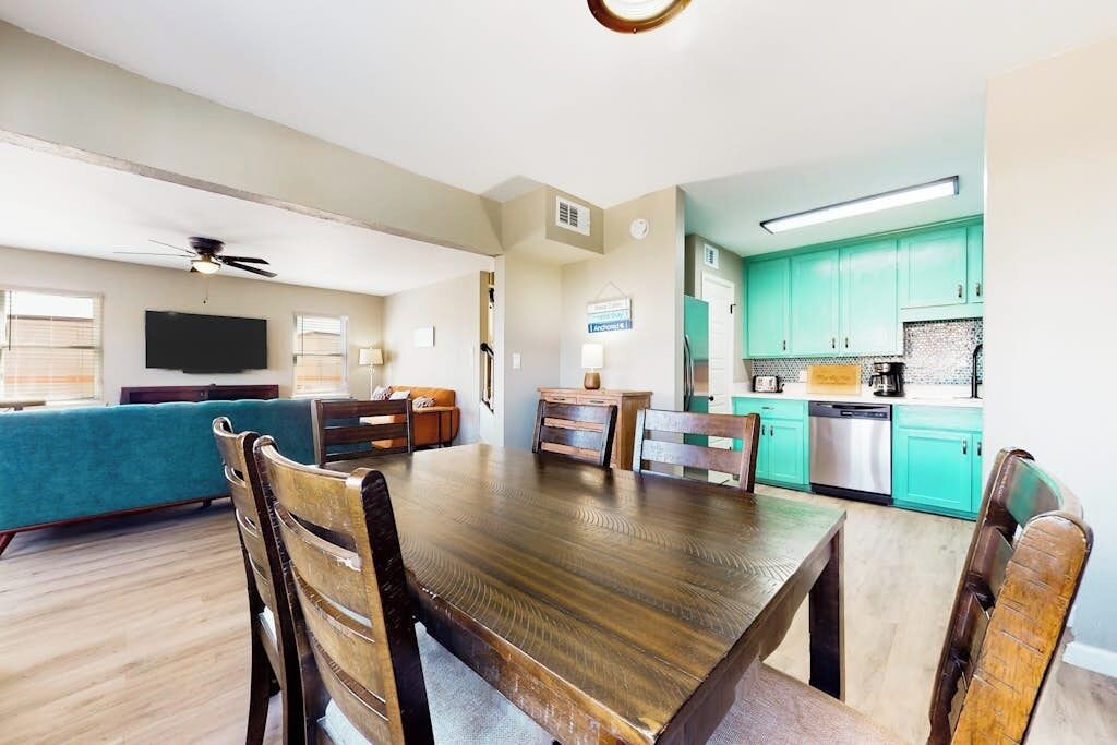 Uma sala de estar moderna com uma mesa de jantar de madeira e cadeiras, um sofá e uma televisão.