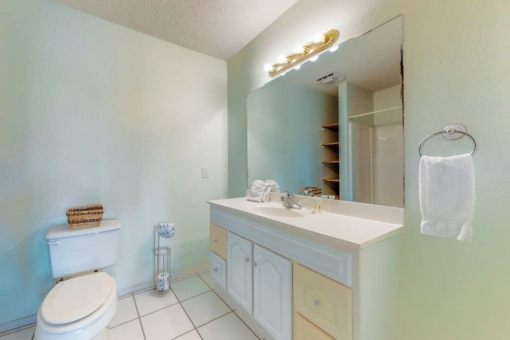 Une salle de bain comprenant des toilettes, un meuble-lavabo avec un miroir et un porte-serviettes.