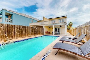 A swimming pool with lounge chairs and a wooden fence. - Casa de la Isla/Mars Island Unit A (South Padre Island)