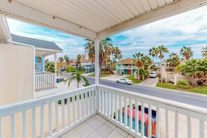 A balcony with a view of a residential street, palm trees, and houses. - Casa de la Isla/Mars Island Unit A (South Padre Island)