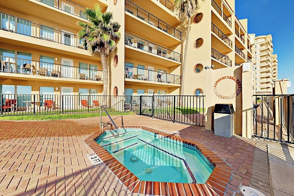 A hotel with a swimming pool, multiple balconies, and a brick patio area.
