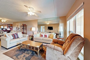 A living room with a sofa, armchair, coffee table, and a ceiling fan. - Suntide II Condominiums #308 (South Padre Island)