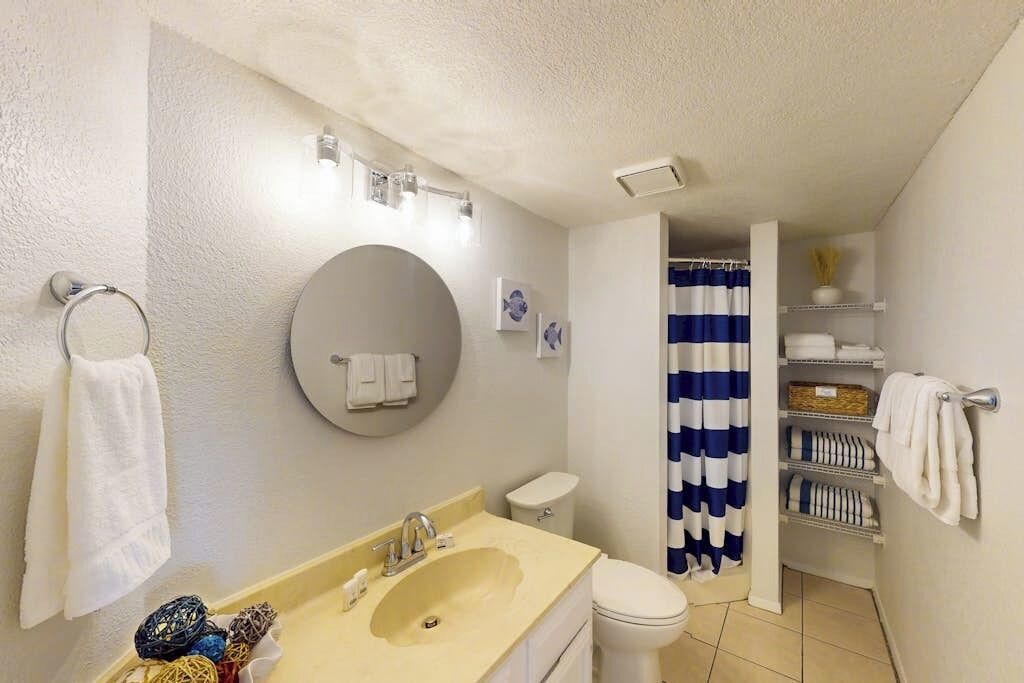 A bathroom with a sink, toilet, and shower curtain.