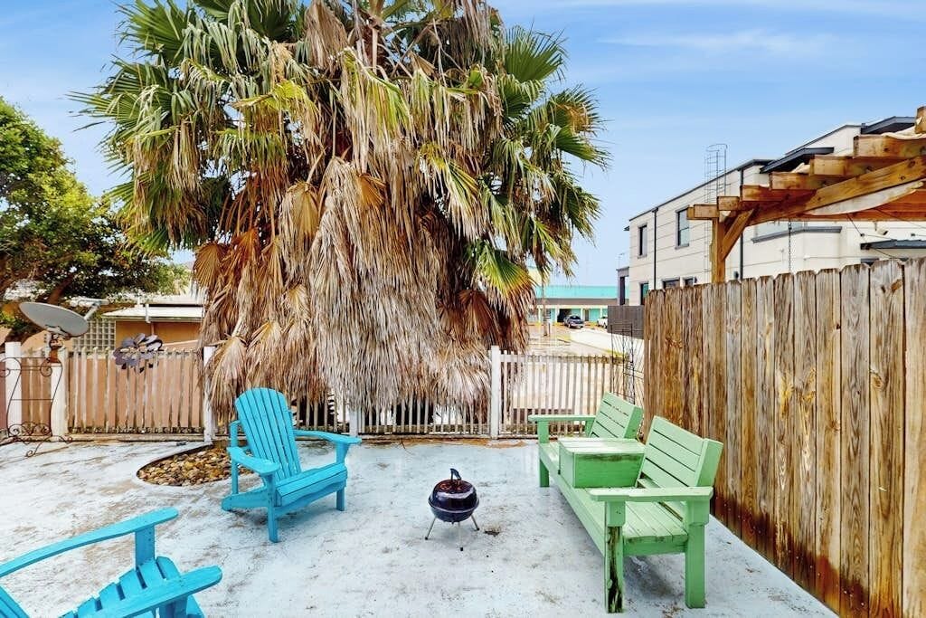 A backyard with a palm tree, a barbecue grill, and outdoor furniture.