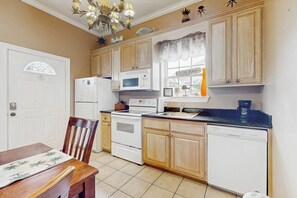 A kitchen with wooden cabinets, a white refrigerator, a stove, a microwave, and a dishwasher. - Casa Emilio II Condominiums 101A (South Padre Island)
