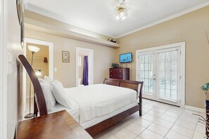 Een slaapkamer met een bed, een dressoir, een televisie en een schuifglazen deur.