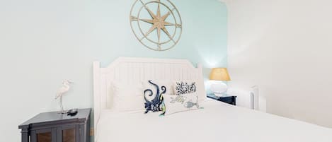 A bedroom with a bed, a nightstand, a wall-mounted compass, and a lamp.