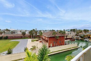 A residential area with a swimming pool, a red building, and a clear sky. - Las Marinas Condominiums 405 (South Padre Island)