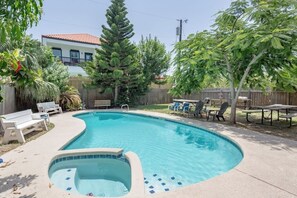 Piscina com hidromassagem, cercada por espreguiçadeiras e um muro de madeira.