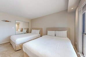 Une chambre d’hôtel avec deux lits, un grand miroir et une fenêtre.