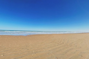 A sandy beach with footprints leading to the water. - Suntide II Condominiums #107 (South Padre Island)