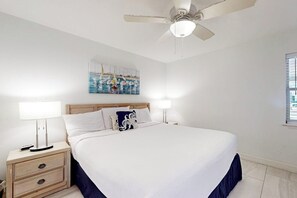 Ein Schlafzimmer mit einem großen Bett, zwei Nachttischen mit Lampen, einem Deckenventilator und einem Gemälde an der Wand.