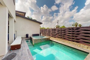 A modern outdoor pool area with a wooden fence, lounge chairs, and a clear sky. - Casa Sol Y Mar - Private Pool, Steps to the Sand (Port Isabel)