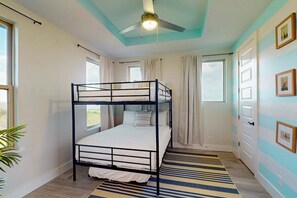 A room with a bunk bed, a ceiling fan, a window with curtains, and a striped rug. - Casa Sol Y Mar - Private Pool, Steps to the Sand (Port Isabel)