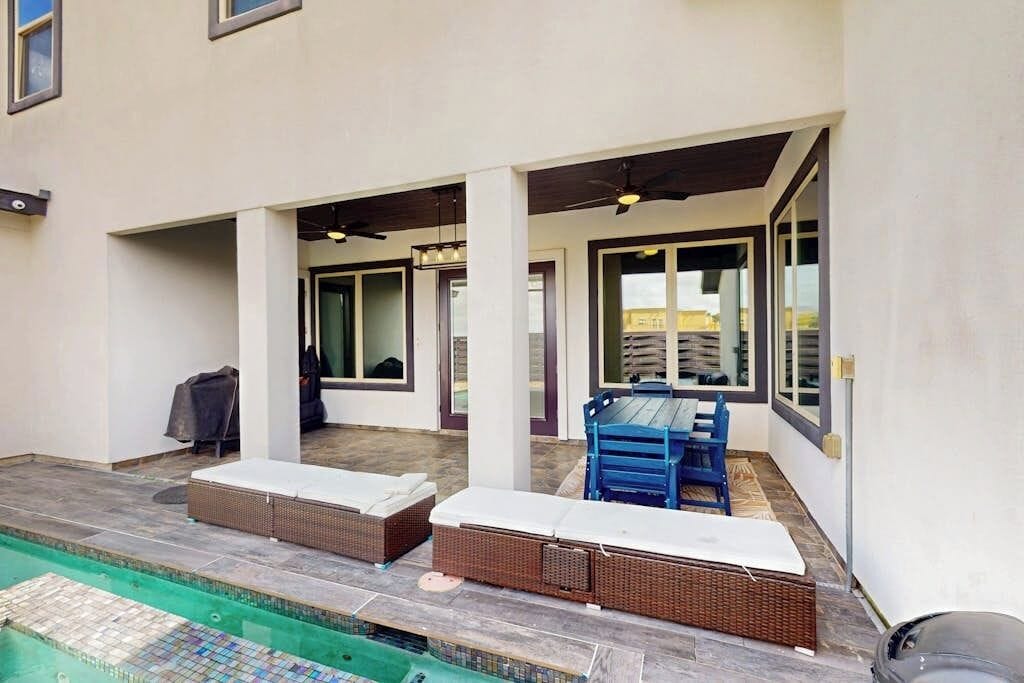 Un espace extérieur abrité comprenant une piscine, des fauteuils et une table à manger.