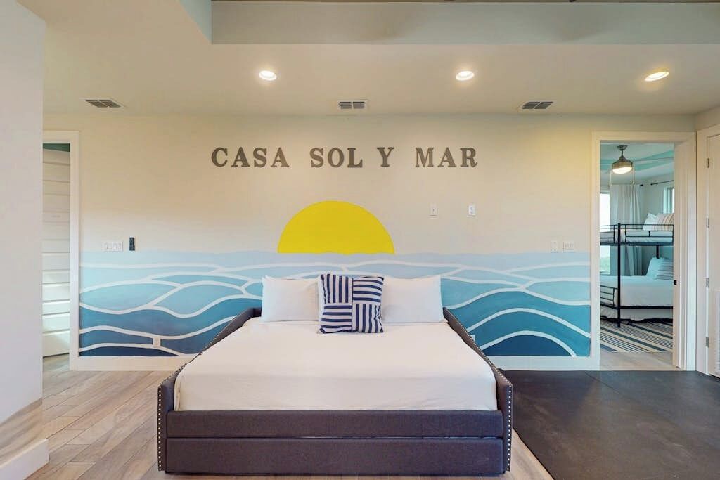 Une chambre à coucher avec un lit, une peinture murale et une porte donnant sur une autre pièce.