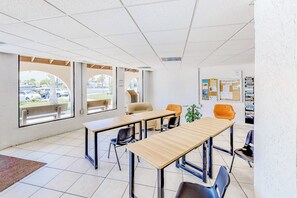 Un salón de conferencias con una gran mesa, sillas y un panel de anuncios con información sobre huracanes.