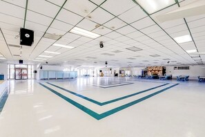 A spacious indoor area with a high ceiling, a central open space, and seating arrangements. - Long Island Village 349 Sand Dollar (Port Isabel)