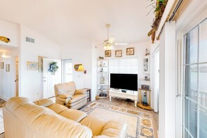 A living room with a sofa, television, and decorative items. - Long Island Village 349 Sand Dollar (Port Isabel)