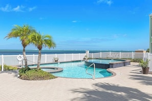 A swimming pool with a view of the ocean, surrounded by a white fence and palm trees. - Las Joyas Bayview Home #216 (Port Isabel)
