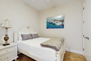Ein Schlafzimmer mit einem Bett, einem Nachttisch, einer Lampe und einem Bild an der Wand.