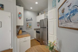 A kitchen with white cabinets, a stainless steel refrigerator, and a wooden countertop. - Beach Club - Seas the Day (Corpus Christi)