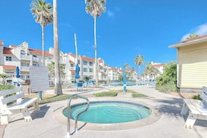 A pool area with lounge chairs, a hot tub, and a sign indicating spa rules. - Beach Club - Seas the Day (Corpus Christi)