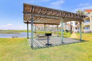 A covered outdoor area with a wooden pergola, a bench, and a trash bin. - Beach Club 173 & 174 (Corpus Christi)